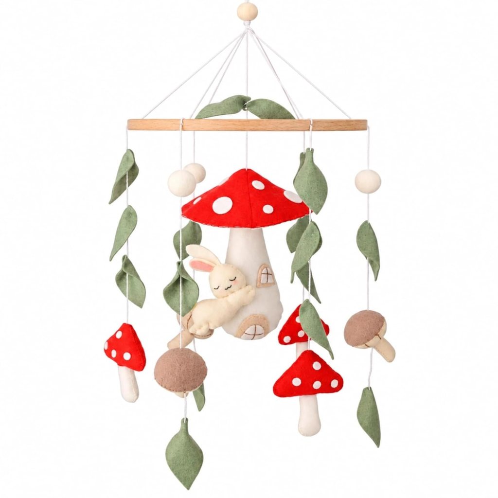 A whimsical baby mobile featuring plush mushrooms, leaves, and a sleeping bunny nestled against a mushroom house.