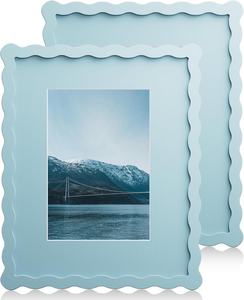 Two light blue scalloped photo frames displaying a scenic landscape with snow-capped mountains and a bridge over water.