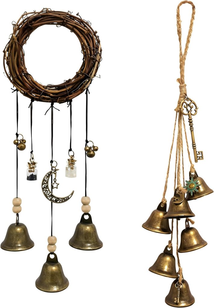 A decorative wall hanging featuring a circular wreath made of twigs, adorned with bells, a crescent moon, and charms, alongside another hanging with multiple bronze bells and a vintage key.
