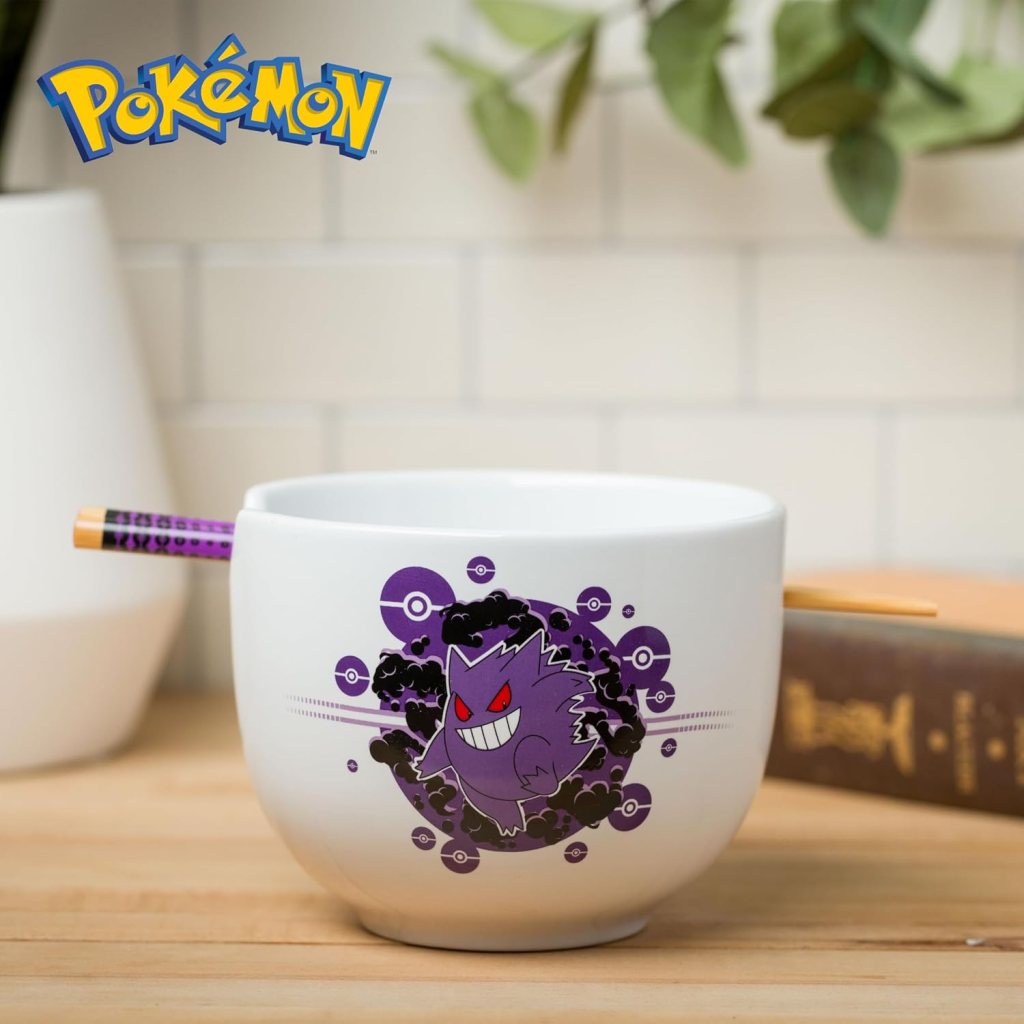 A white bowl featuring a vibrant graphic of a purple Pokémon character with red eyes and a mischievous grin, surrounded by circular Pokéball designs. A pair of chopsticks is resting on the edge of the bowl.