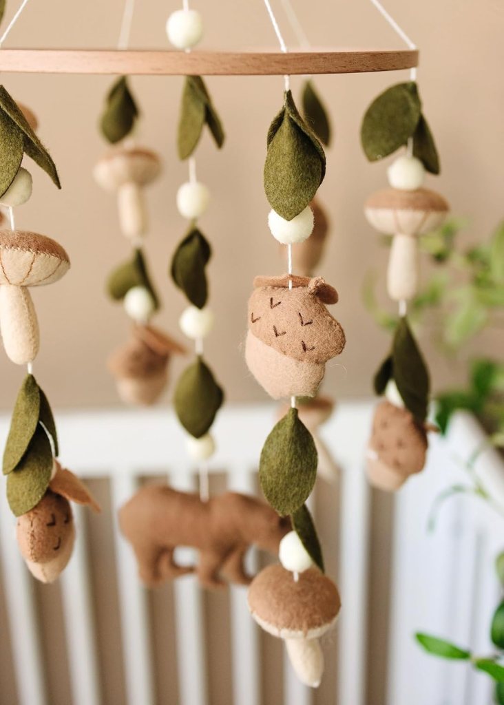 Felt mobile featuring woodland animals, mushrooms, and leaves, hanging from a wooden ring.