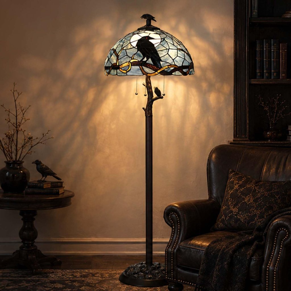 A decorative floor lamp with a stained glass shade featuring a crow design, illuminating a cozy living space with a leather armchair and dark wooden furniture.