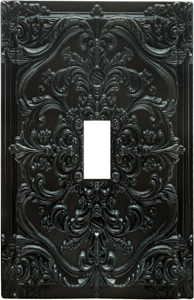 Black ornate light switch plate with intricate floral designs and a rectangular opening in the center.