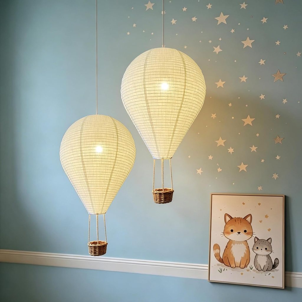 Two pendant lights designed as hot air balloons in a room with a light blue wall, decorated with stars. A framed illustration of a cat and a kitten is visible nearby.