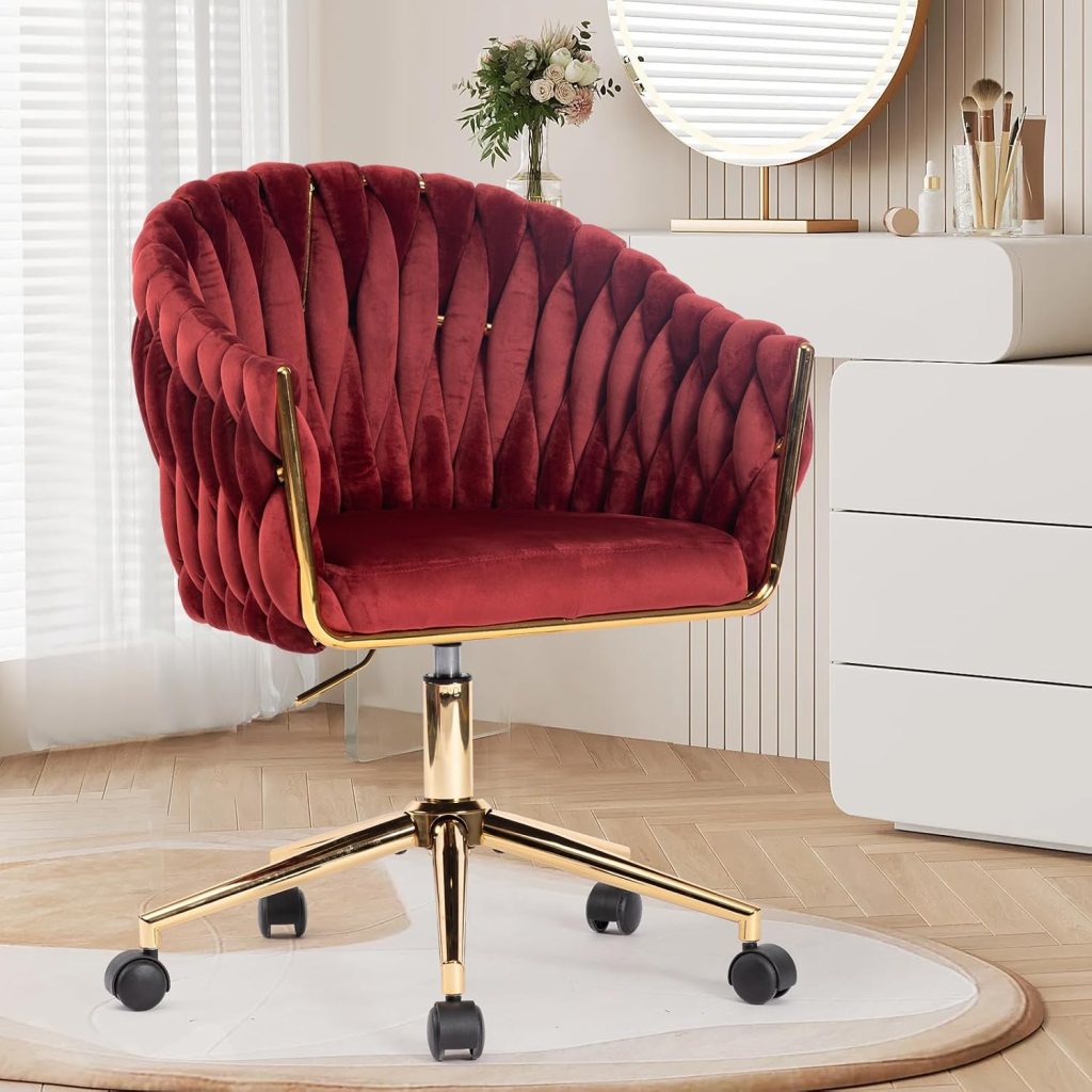 A stylish red velvet office chair with a ribbed design and gold accents, set in a modern workspace with a soft light background.