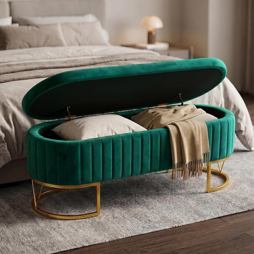 A stylish green velvet storage bench with a curved top, open to reveal pillows and a beige throw blanket, placed in a modern bedroom setting.