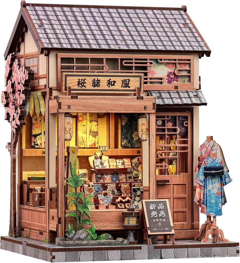 A traditional Japanese clothing shop storefront featuring wooden architecture, cherry blossom decorations, and various colorful kimonos displayed inside.