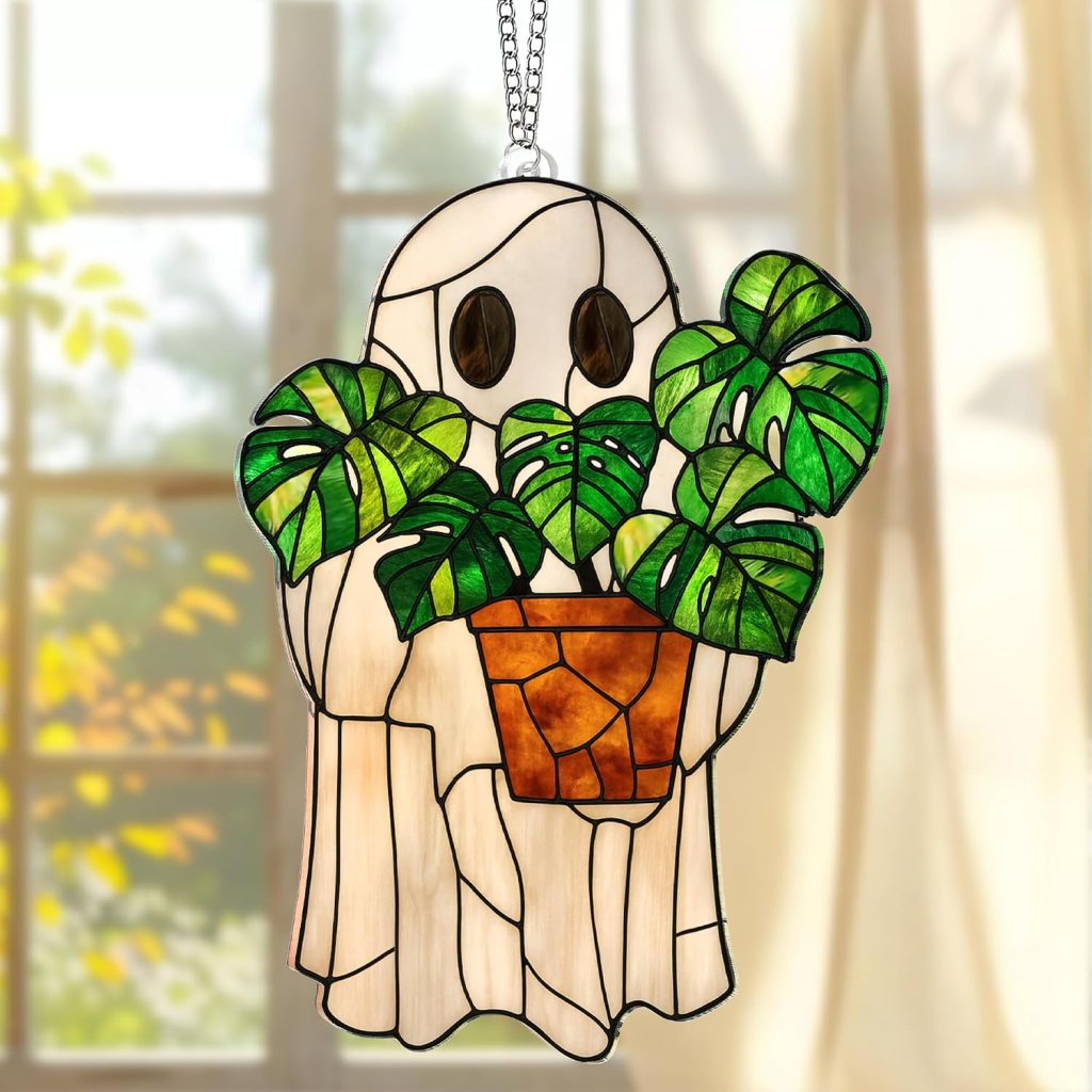 A stained glass decoration depicting a ghost holding a potted plant, featuring vibrant green leaves, with a soft background of sunlight filtering through a window.