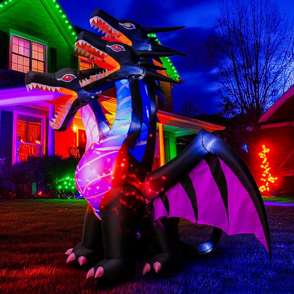 Inflatable three-headed dragon decoration illuminated with colorful lights in a front yard at night.