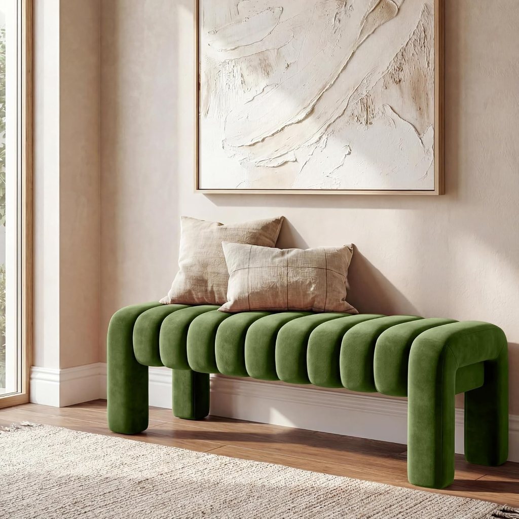 A stylish green upholstered bench with rounded cushions, positioned against a light-colored wall, featuring a textured abstract artwork above it and two beige pillows on the seat.