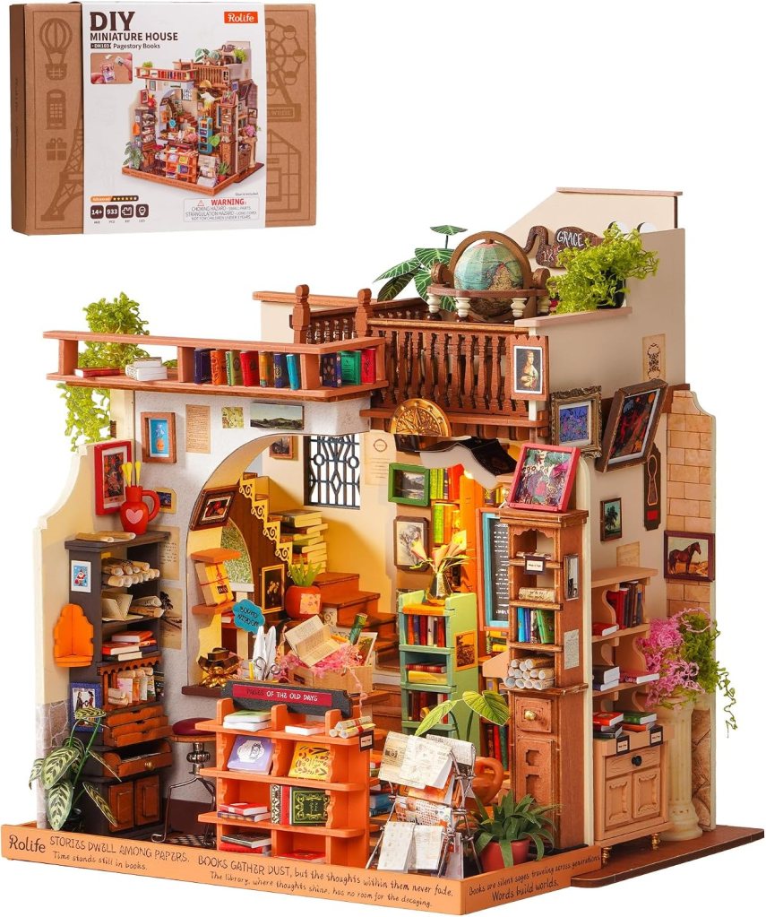 A detailed DIY miniature house depicting a cozy library setting with bookshelves, decorative plants, and a globe. The scene includes various crafted items like books, papers, and figurines, showcasing intricate design elements.
