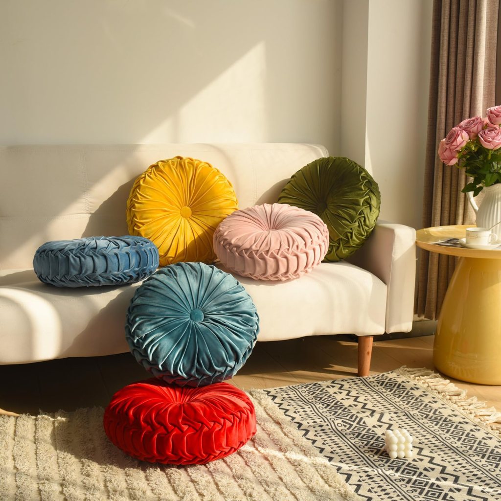 A collection of round, decorative cushions in various colors (yellow, blue, pink, green, and red) arranged on a light-colored sofa, with natural sunlight illuminating the scene.