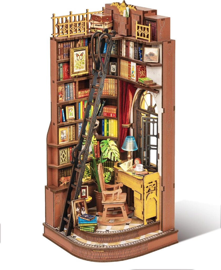 A detailed miniature library scene featuring shelves filled with books, a cozy desk with a chair, plants, and a ladder leading to an upper level.