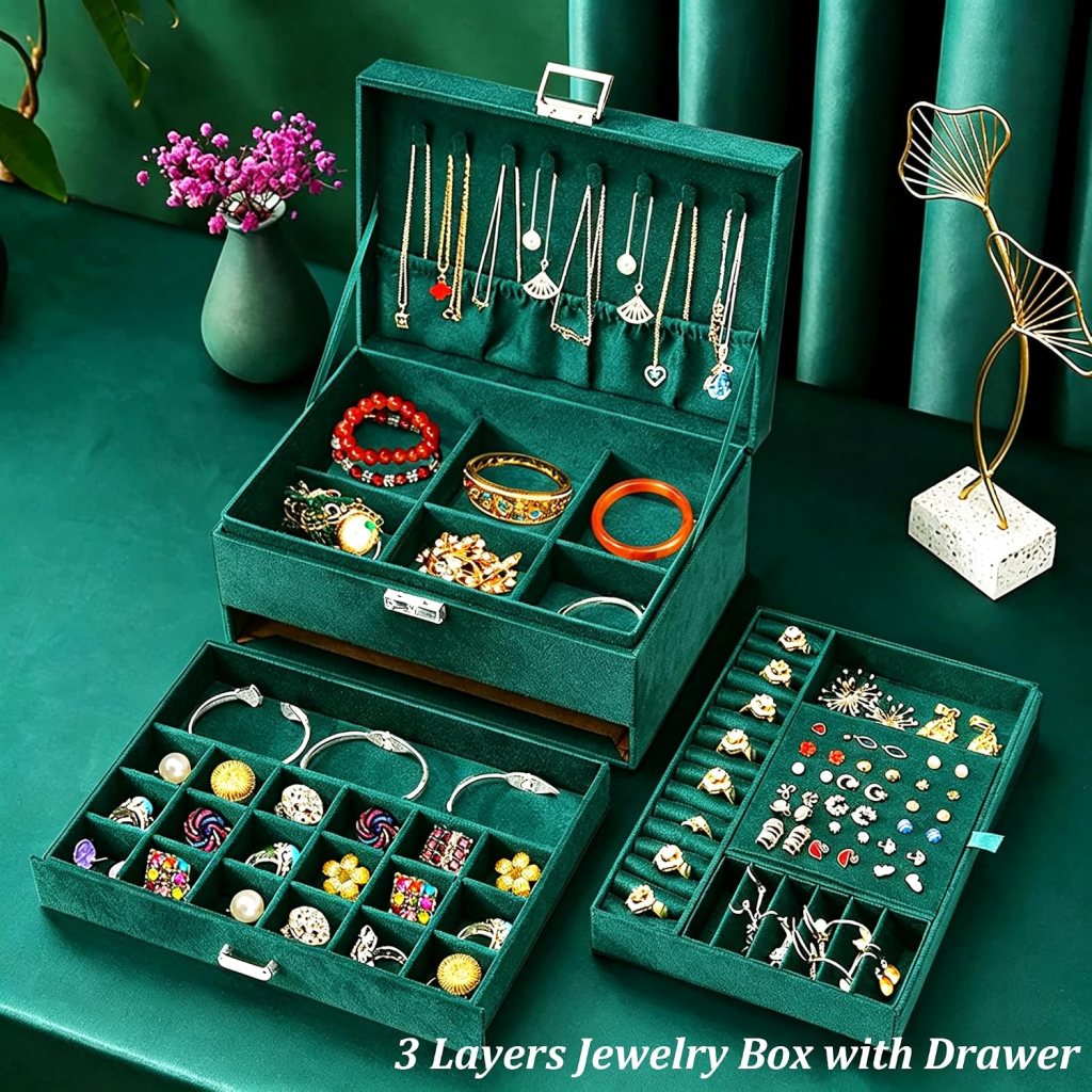 A green velvet jewelry box with three layers and a drawer, showcasing various necklaces, bracelets, and rings neatly organized inside.