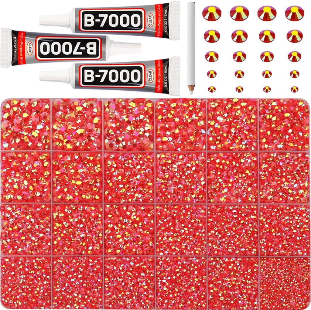 A collection of red rhinestone gems arranged in a grid, accompanied by two tubes of B-7000 adhesive, a detailing pencil, and various red and yellow decorative gems.